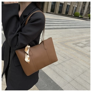 Brown leather tote bag with printed silk scarf detail shown on a model's shoulder