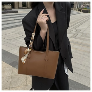 Close-up of vintage brown leather tote bag with elegant floral scarf detail on the handle