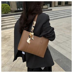Brown faux leather tote bag with decorative silk scarf shown worn on the shoulder