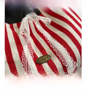 Close-up of red and white striped fabric with white lace and a handmade metal tag