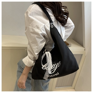 Detail of black nylon tote bag with white lettering and lace bow on female model