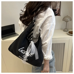 Detail of black nylon tote bag with mcli print and white lace bow in a lifestyle setting