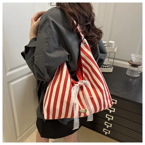 Close-up of red striped canvas tote bag with a white lace bow and handmade label
