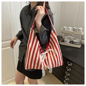 Detail of red striped canvas tote bag featuring a large white lace bow and handmade tag
