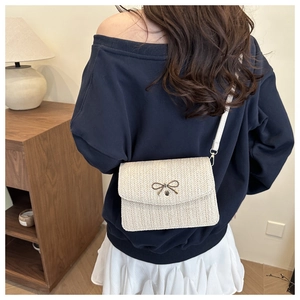 Close-up of cream woven crossbody bag with gold butterfly clasp on a female model