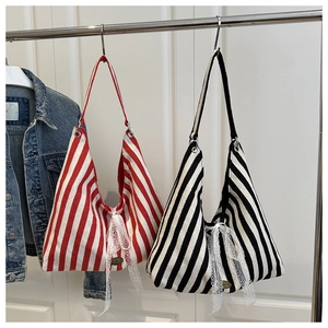 Detail of striped canvas tote bag with elegant white lace bow and small metal logo