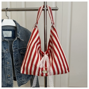 Detail of red and white striped tote bag with lace bow and circular handmade label