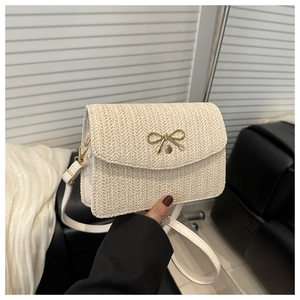 Close-up of cream woven crossbody bag with elegant gold bow metal buckle detail