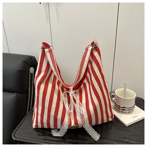 Detail of red and white striped tote bag with lace bow and handmade metal plaque