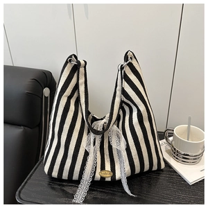 Close-up of striped canvas tote bag featuring a white lace bow and handmade metal plate