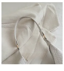 Detailed close-up of the white woven textured handbag handle with gold metal ring buckles