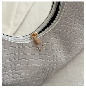 Macro shot of smooth gold zipper and white woven texture on a minimalist handbag
