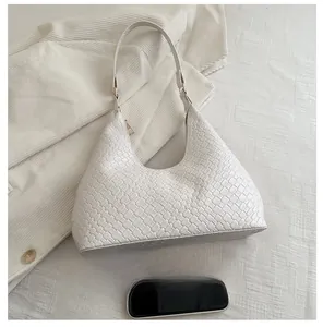 Detailed view of white woven hobo bag showing leather texture next to a phone for scale
