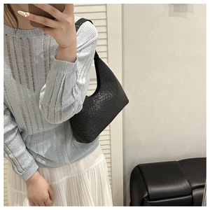 Close-up of black woven leather crescent underarm bag showing detailed texture and strap