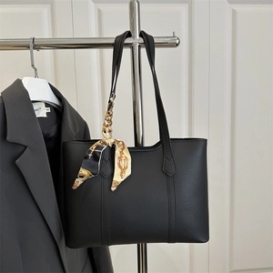 Classic black tote bag with printed silk scarf hanging on a grey suit jacket
