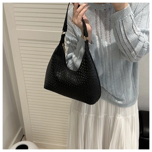 Detail of black woven leather hobo bag with fine texture and gold metal hardware