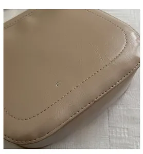 Close-up of beige leather bucket bag with silver Fashion & Bags logo and fine stitching