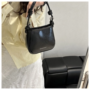 Detail of black oil wax leather handbag with knot strap and silver fashion logo