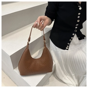 Close-up of caramel woven texture on a premium crescent shoulder bag with gold zipper