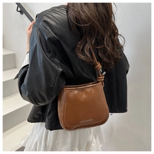 Detail of caramel brown bucket bag featuring knotted strap and white FASHION & BAGS text