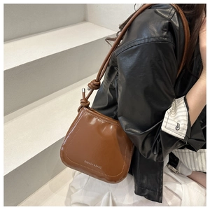 Close-up of brown leather shoulder bag with knotted strap and FASHION & BAGS logo