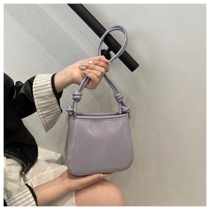 Detail of lavender leather crossbody bag with knot handle and embossed logo on base