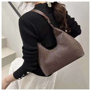 Detail of deep brown hobo bag featuring woven texture and ergonomic shoulder handle