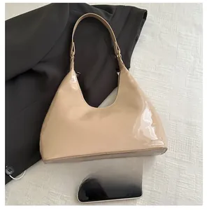 Glossy beige patent leather underarm bag shown next to a smartphone for size reference