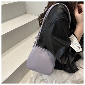 Detail of light purple leather crossbody bag with knot strap design and magnetic flap