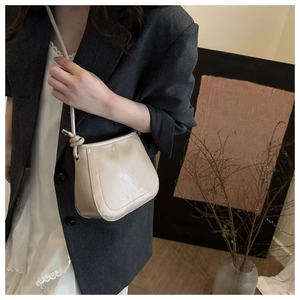 Close-up of minimalist apricot bucket bag with knotted strap and printed text detail