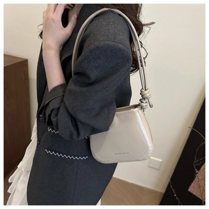 Detail view of beige shoulder bag featuring a unique knotted strap and sleek PU leather