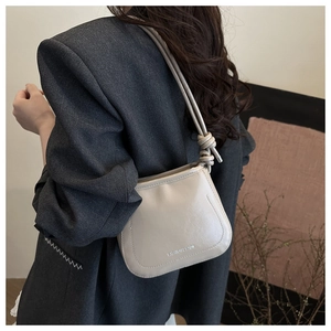 Close-up of the stylish knot detail on the shoulder strap of a cream crossbody bag