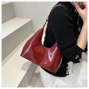 Detail van rode laklederen hobo-tas met glanzende afwerking en modern halve maan ontwerp