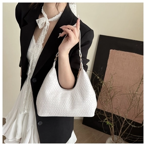Detail of white woven leather hobo bag with gold ring hardware on a model with black blazer