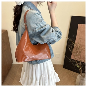 Detail van de hobo-tas in karamel lakleer met gladde textuur op een vrouwelijk model