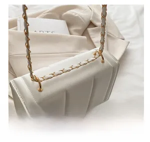 Detail of off-white quilted crossbody bag featuring elegant vertical pleats and gold chain
