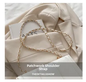 Detail of white quilted crossbody bag featuring a gold metal and leather chain strap