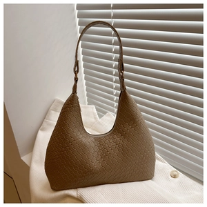 Detailed view of woven hobo bag texture and gold buckle on a white knit sweater