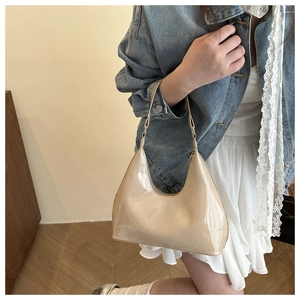 Detailopname van het glanzende beige lakleer op de maanvormige schoudertas voor dames