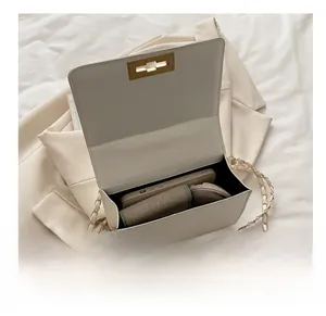 Internal capacity of the beige chain bag showing phone, powder and daily essentials