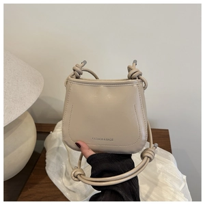 Detail of beige glossy leather handbag with unique knotted shoulder strap design