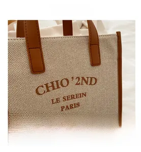 Detail view of the canvas tote bag showing high-quality leather handles and stitching
