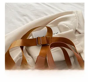 Detail of adjustable nylon strap and metal buckle on woven beige shoulder tote bag