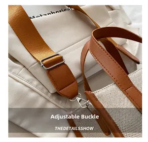Detail of adjustable silver buckle and brown leather strap on a beige canvas tote bag