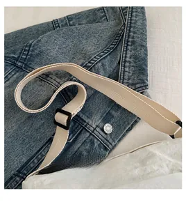 Detail of white wrinkled nylon crossbody bag with wide canvas strap on denim backdrop