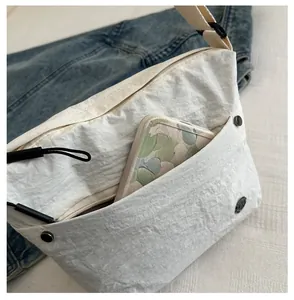 Detail of front storage pocket on white canvas messenger bag with a phone inside