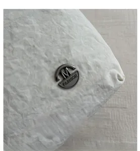 Macro detail of off-white wrinkled nylon fabric with a metallic brand logo