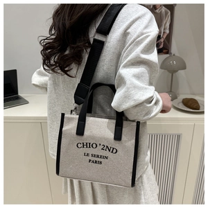 Canvas tote bag with black trim and wide strap styled in a minimalist indoor workspace