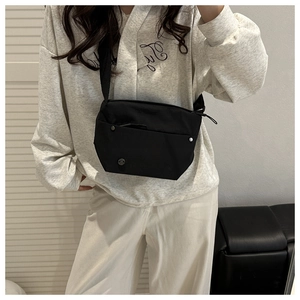 Detail of black nylon crossbody bag with metal M logo and silver rivet accents