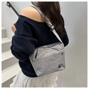 Detail of grey pleated nylon crossbody bag showing water-resistant texture and logo